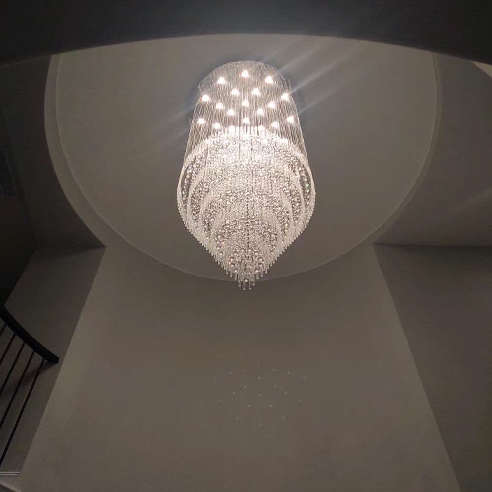 Elegant crystal chandelier hanging from a circular ceiling in a modern entryway.