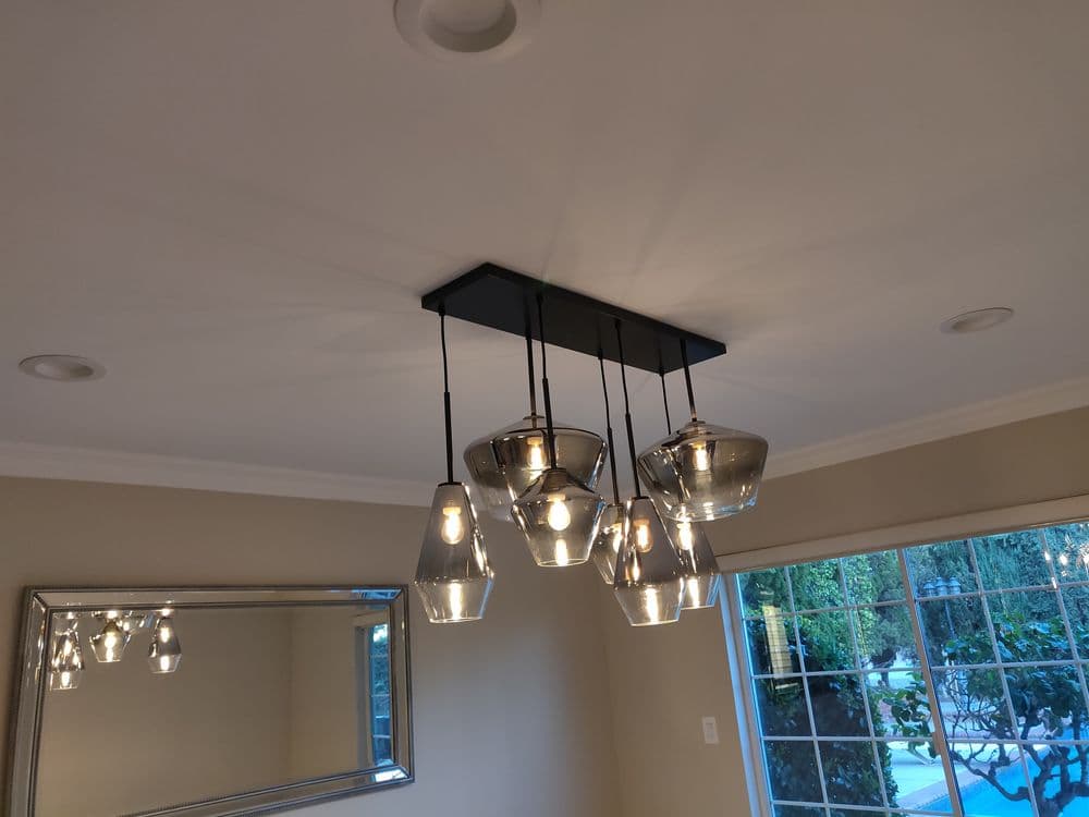 Modern pendant light fixture with multiple glass shades hanging from a sleek black ceiling mount.