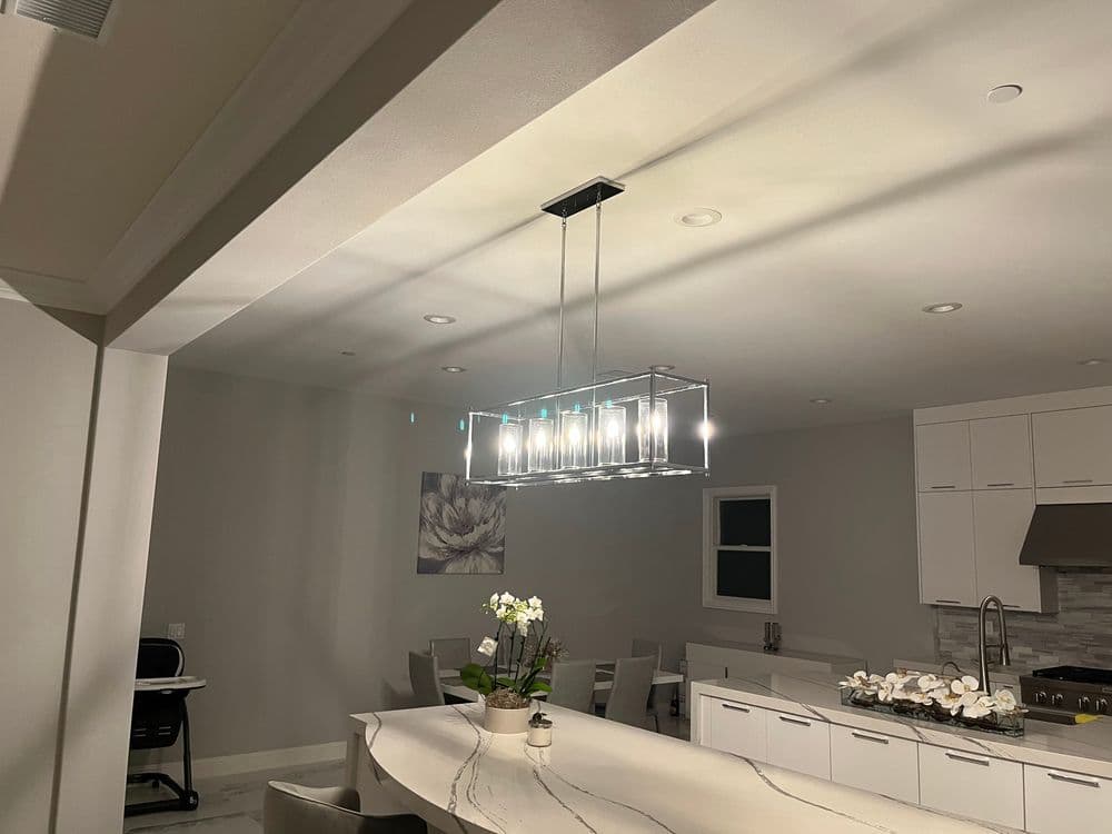 Modern kitchen featuring a stylish pendant light, white cabinets, and elegant decor.
