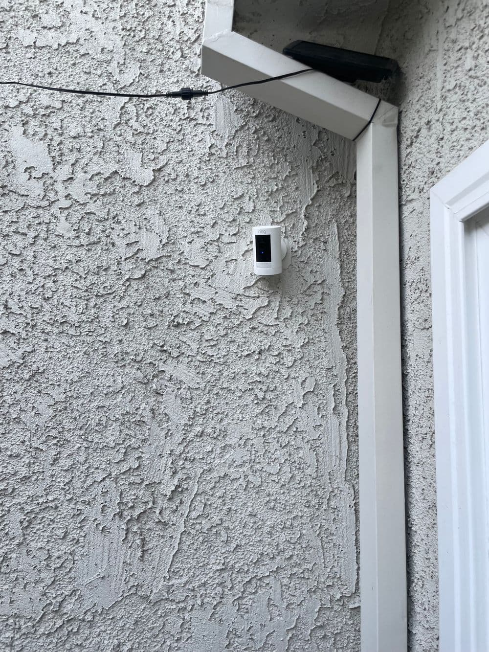Exterior wall showing a security camera mounted near a door, textured surface visible.