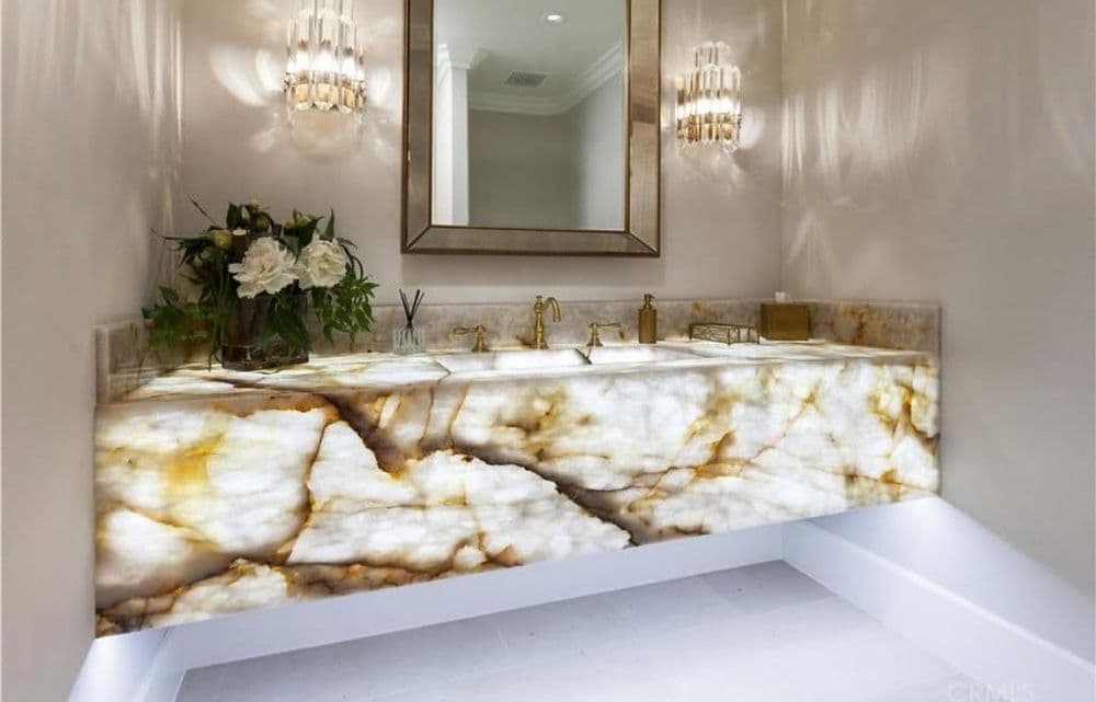 Luxurious modern bathroom with onyx countertop, double sinks, elegant lighting, and mirror.